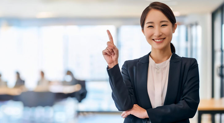 人差し指を立てる女性社員の写真